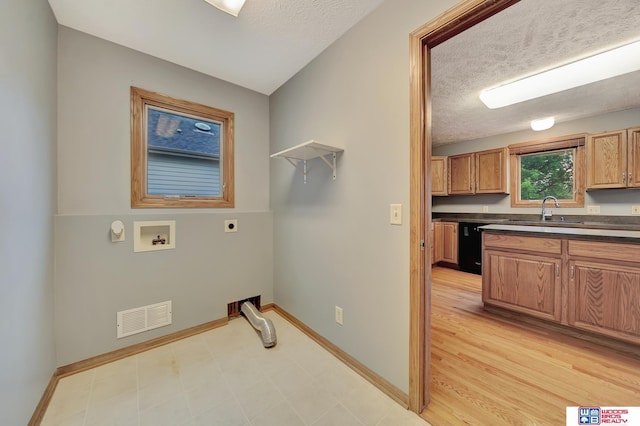 7910 Red Oak Rd, Lincoln, NE 68516 - laundry room featuring hookup for an electric dryer, a sink, hookup for a washing machine, baseboards, and a textured ceiling