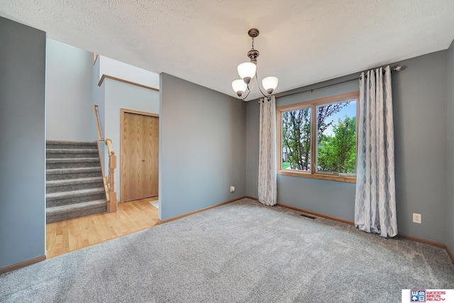 7910 Red Oak Rd, Lincoln, NE 68516 - carpeted empty room featuring a chandelier, stairway, baseboards, and a textured ceiling