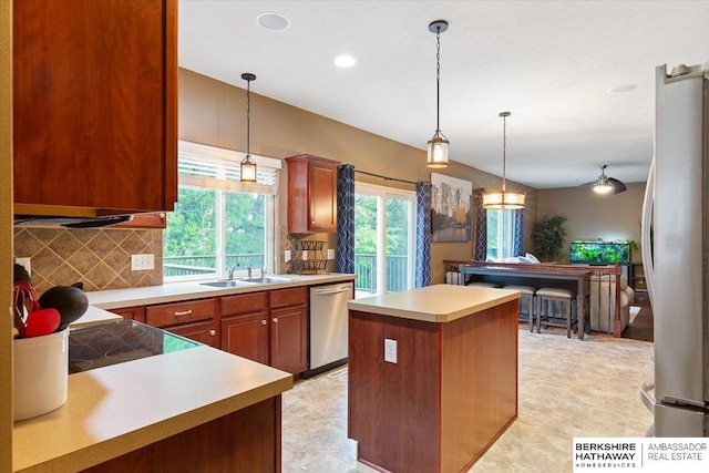 kitchen with freestanding refrigerator, stainless steel dishwasher, backsplash, a center island, and light countertops