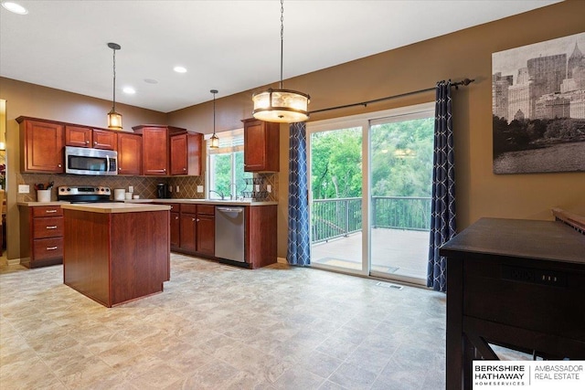 kitchen featuring stainless steel appliances, tasteful backsplash, light countertops, a kitchen island, and hanging light fixtures