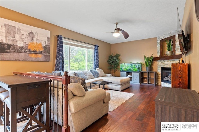 living room featuring ceiling fan, wood finished floors, and a stone fireplace