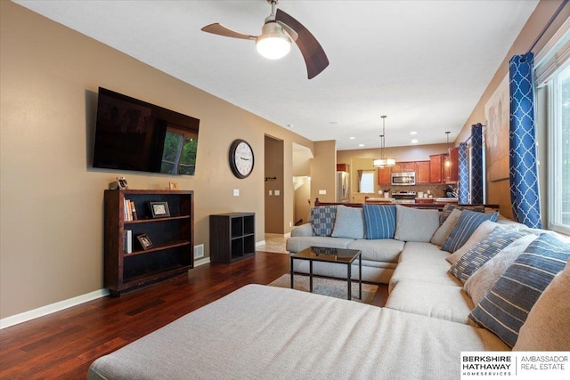 living area featuring dark wood-type flooring, a ceiling fan, and baseboards