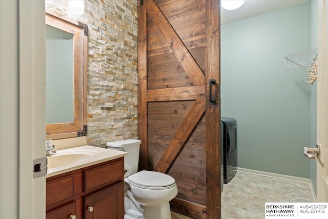 bathroom with toilet, vanity, and washer / clothes dryer