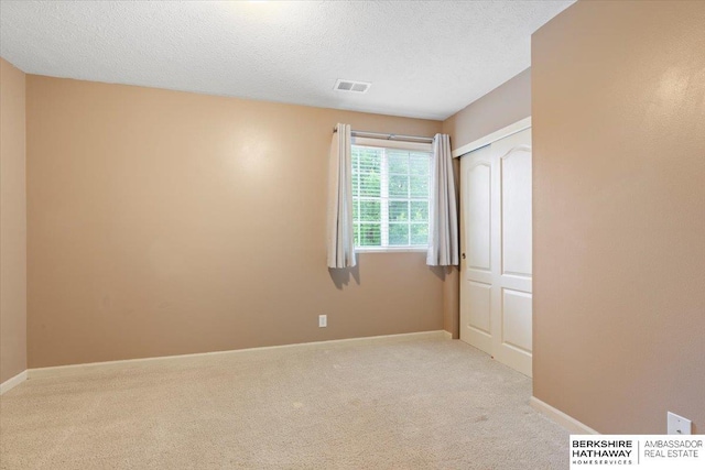 unfurnished bedroom featuring carpet floors, a textured ceiling, baseboards, and a closet