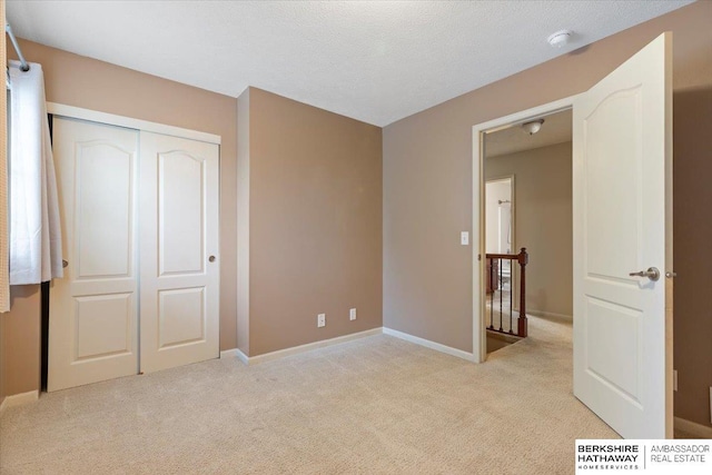 unfurnished bedroom featuring light carpet, a closet, and baseboards