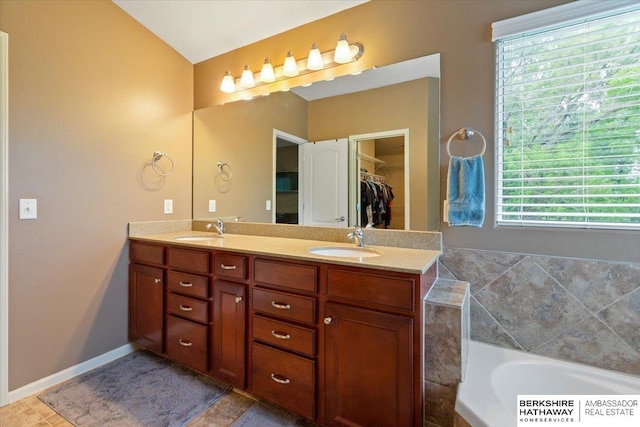 full bath with double vanity, a bath, and a walk in closet