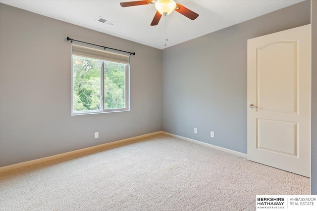 carpeted spare room featuring a ceiling fan and baseboards
