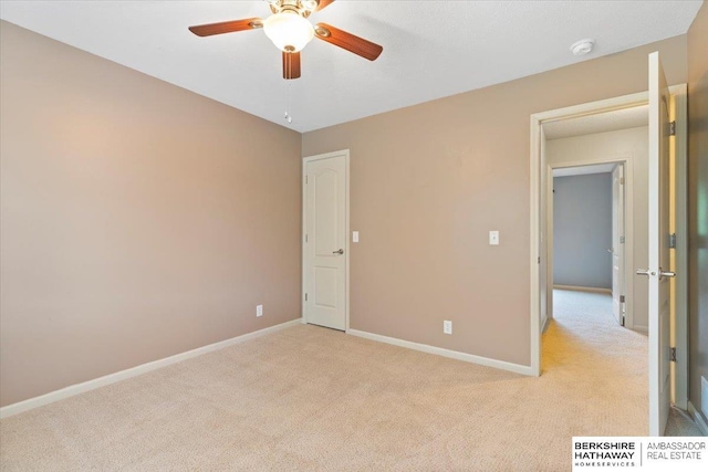 empty room featuring light carpet, a ceiling fan, baseboards, and a smoke detector