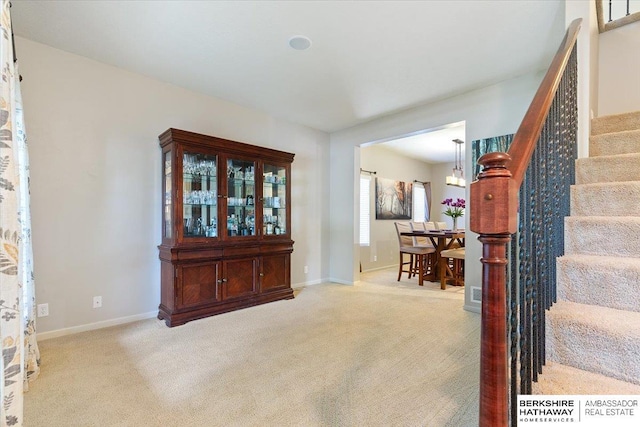 carpeted foyer with stairway, baseboards, and a chandelier