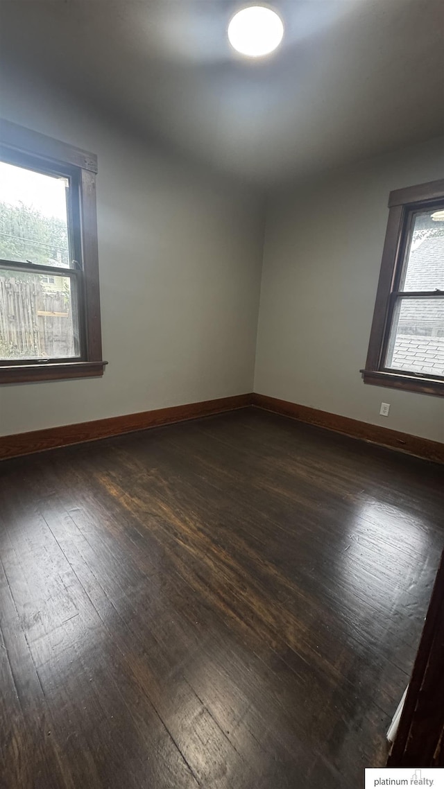 empty room featuring dark wood-style floors and baseboards