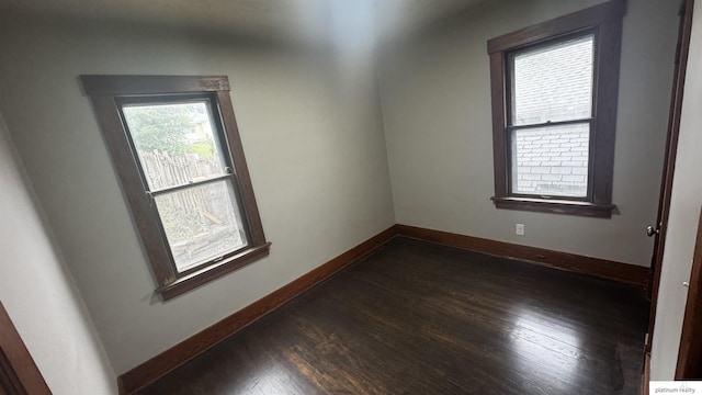 unfurnished room featuring baseboards and dark wood finished floors