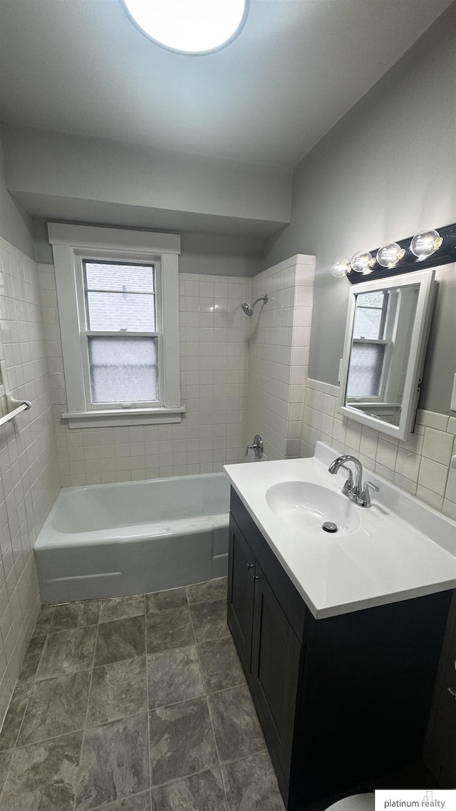 bathroom featuring tile walls, vanity, and washtub / shower combination
