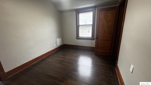 spare room with dark wood-style flooring and baseboards