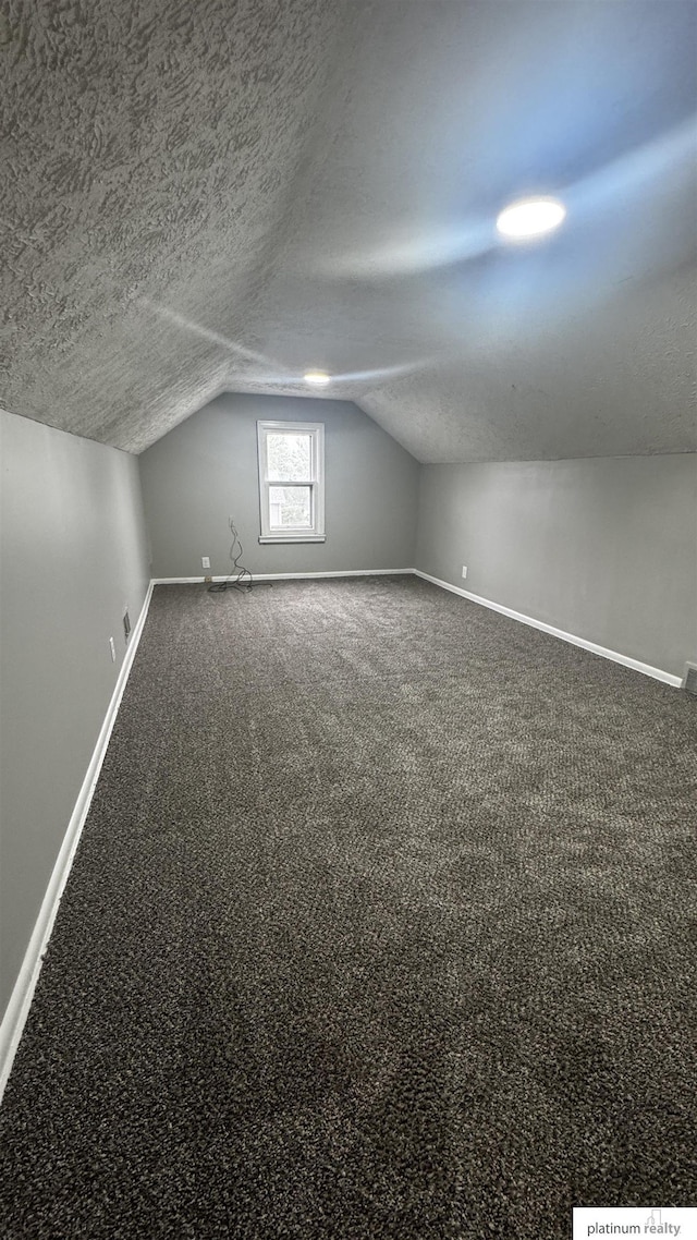 bonus room with lofted ceiling, baseboards, a textured ceiling, and carpet