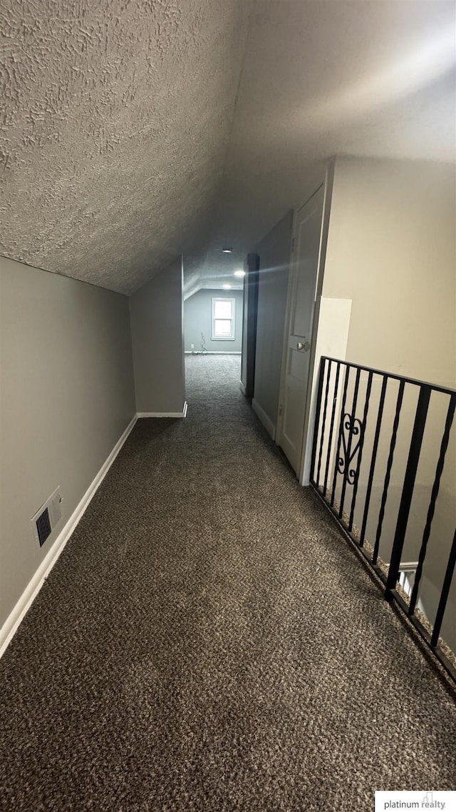 bonus room featuring dark colored carpet, lofted ceiling, baseboards, and a textured ceiling