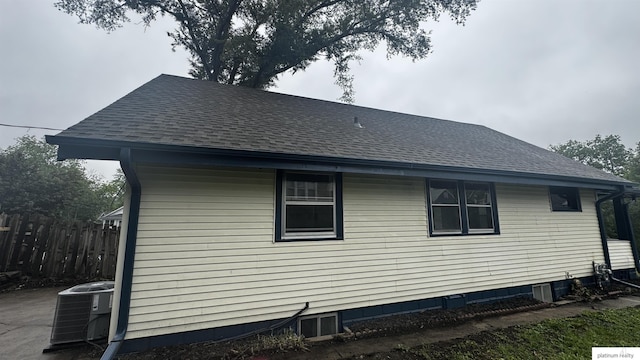 view of side of property with central air condition unit and roof with shingles