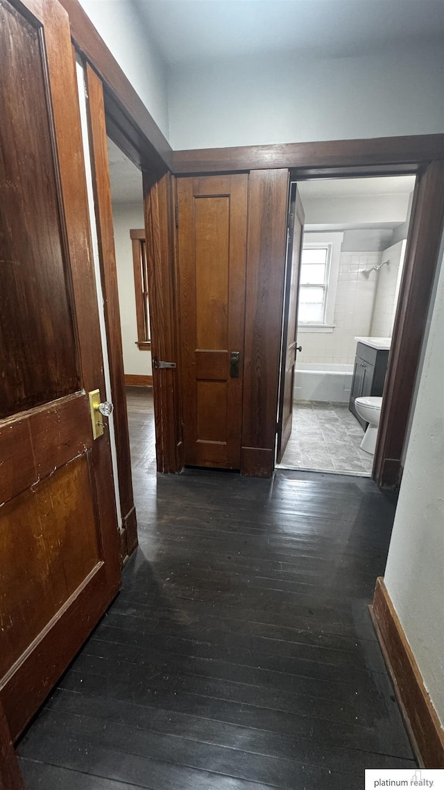 hallway featuring dark wood-style floors and baseboards