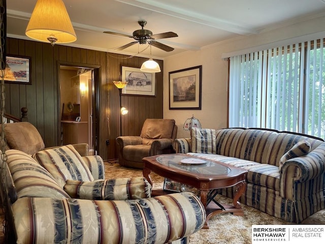 1200 H St, Pawnee City, NE 68420 - living room featuring a ceiling fan, ornamental molding, wooden walls, and beam ceiling