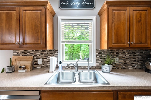 kitchen with a sink, dishwasher, brown cabinets, and tasteful backsplash