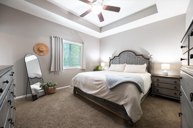 bedroom featuring dark carpet, baseboards, a raised ceiling, and ceiling fan