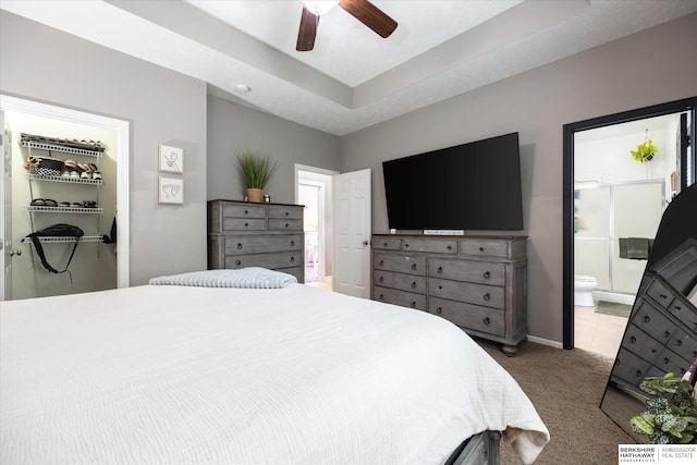 carpeted bedroom with ensuite bath, a spacious closet, baseboards, a closet, and ceiling fan