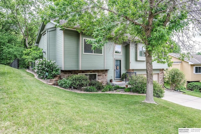 view of front of property with a front lawn, concrete driveway, a garage, and stone siding