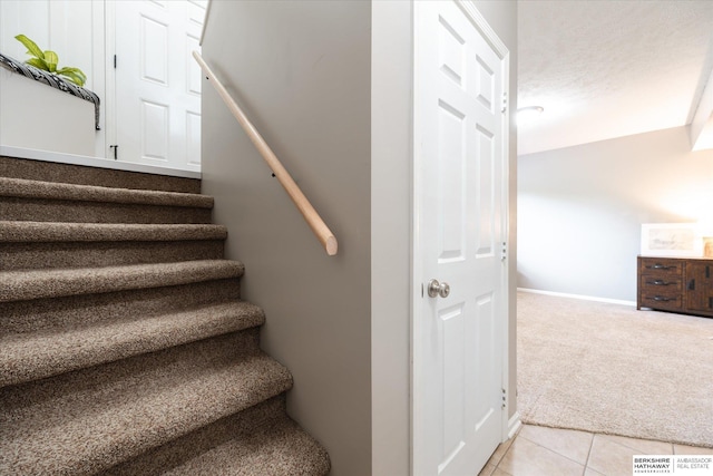 stairs featuring carpet flooring, baseboards, and tile patterned floors