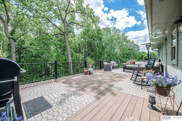 wooden deck with an outdoor hangout area and view of wooded area