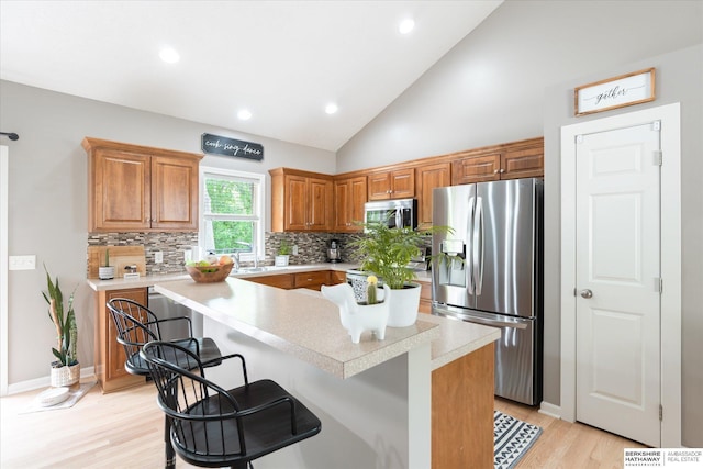 kitchen featuring stainless steel appliances, light countertops, tasteful backsplash, recessed lighting, and light wood-style floors