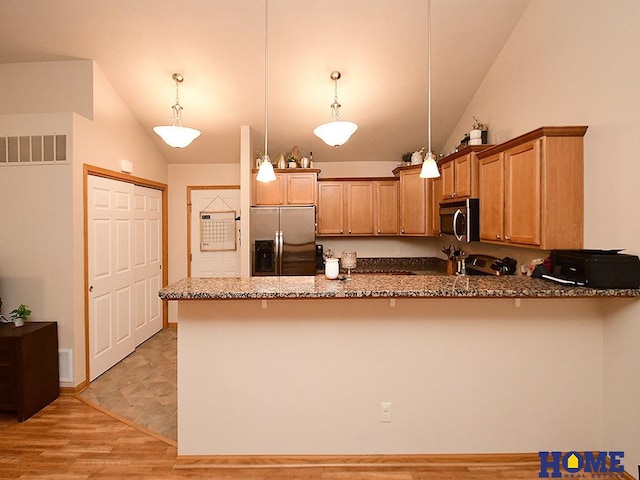 8946 Broken Spoke Dr, Lincoln, NE 68507 - kitchen with appliances with stainless steel finishes, lofted ceiling, dark stone counters, a peninsula, and decorative light fixtures