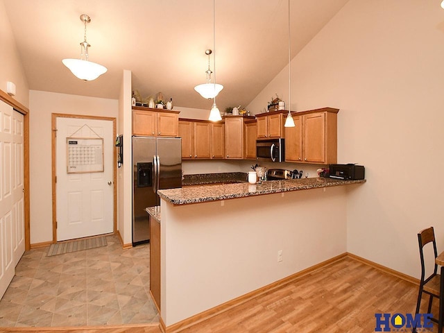 8946 Broken Spoke Dr, Lincoln, NE 68507 - kitchen with appliances with stainless steel finishes, a peninsula, vaulted ceiling, dark stone countertops, and hanging light fixtures