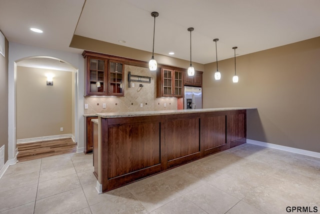 6732 S 169th Ave, Omaha, NE 68135 - kitchen with stainless steel fridge, arched walkways, backsplash, light tile patterned floors, and decorative light fixtures