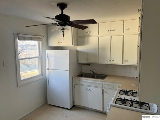 kitchen featuring white appliances, a sink, light countertops, tasteful backsplash, and a ceiling fan