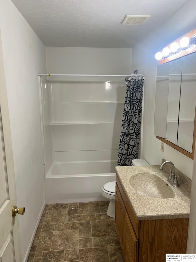 bathroom with toilet, stone finish flooring, shower / bath combo with shower curtain, and vanity