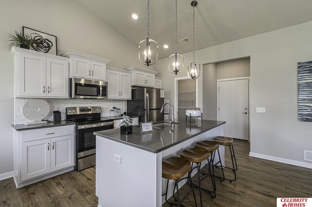 6413 N 168th Ave, Omaha, NE 68116 - kitchen with stainless steel appliances, a sink, dark countertops, tasteful backsplash, and dark wood-type flooring