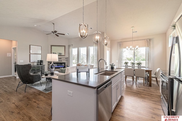 6413 N 168th Ave, Omaha, NE 68116 - kitchen featuring appliances with stainless steel finishes, a sink, a chandelier, dark countertops, and a glass covered fireplace