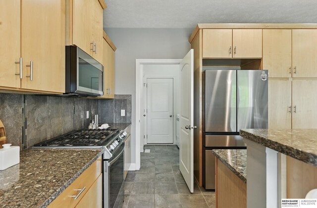 7211 S 174th St, Omaha, NE 68136 - kitchen with appliances with stainless steel finishes, light brown cabinets, dark stone countertops, backsplash, and baseboards