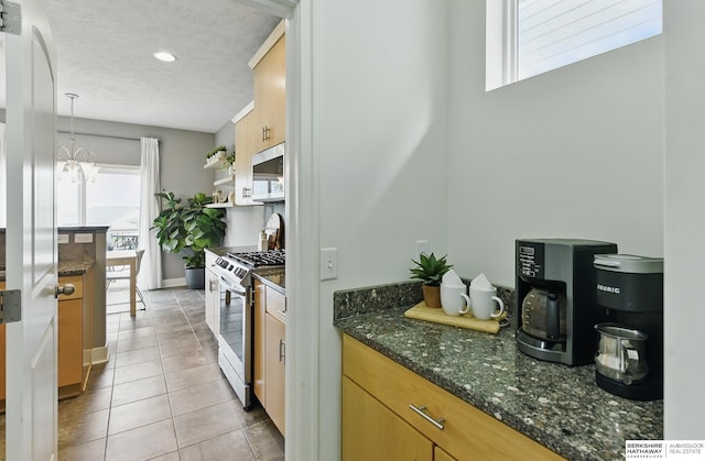 7211 S 174th St, Omaha, NE 68136 - kitchen with stainless steel appliances, healthy amount of natural light, light tile patterned floors, dark stone countertops, and a textured ceiling