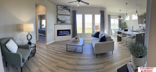 11310 Grebe St, Omaha, NE 68142 - living room with a ceiling fan, a chandelier, light wood-style flooring, and a brick fireplace