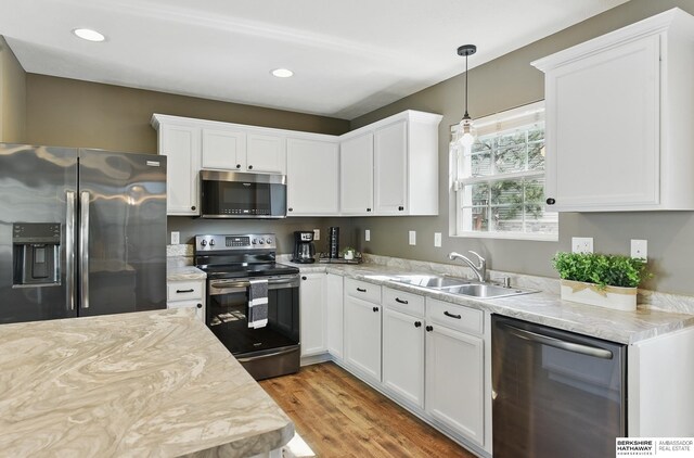 6031 N 167th Ct, Omaha, NE 68116 - kitchen featuring stainless steel appliances, a sink, light wood-style floors, white cabinets, and hanging light fixtures