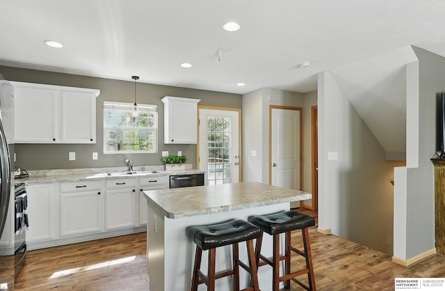 6031 N 167th Ct, Omaha, NE 68116 - kitchen featuring a sink, white cabinets, wood finished floors, a kitchen island, and stainless steel dishwasher