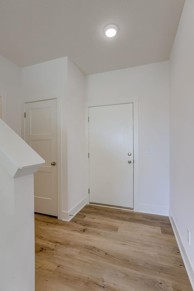 hall with light wood-style floors and baseboards