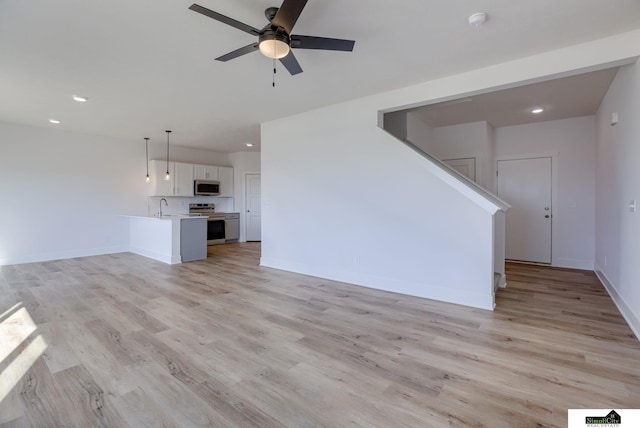 unfurnished living room with ceiling fan, light wood-style flooring, recessed lighting, a sink, and baseboards