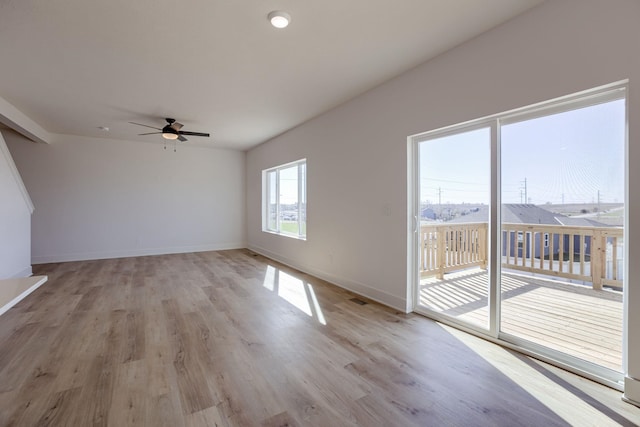 empty room with ceiling fan, light wood-style floors, and baseboards