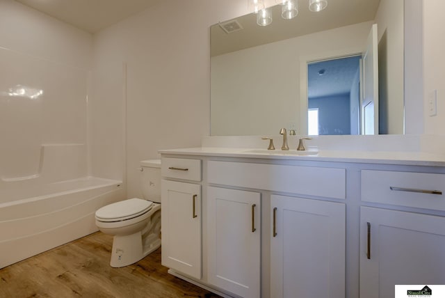 full bath with wood finished floors, toilet, vanity, and bathtub / shower combination