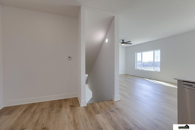 staircase with wood finished floors, ceiling fan, and baseboards