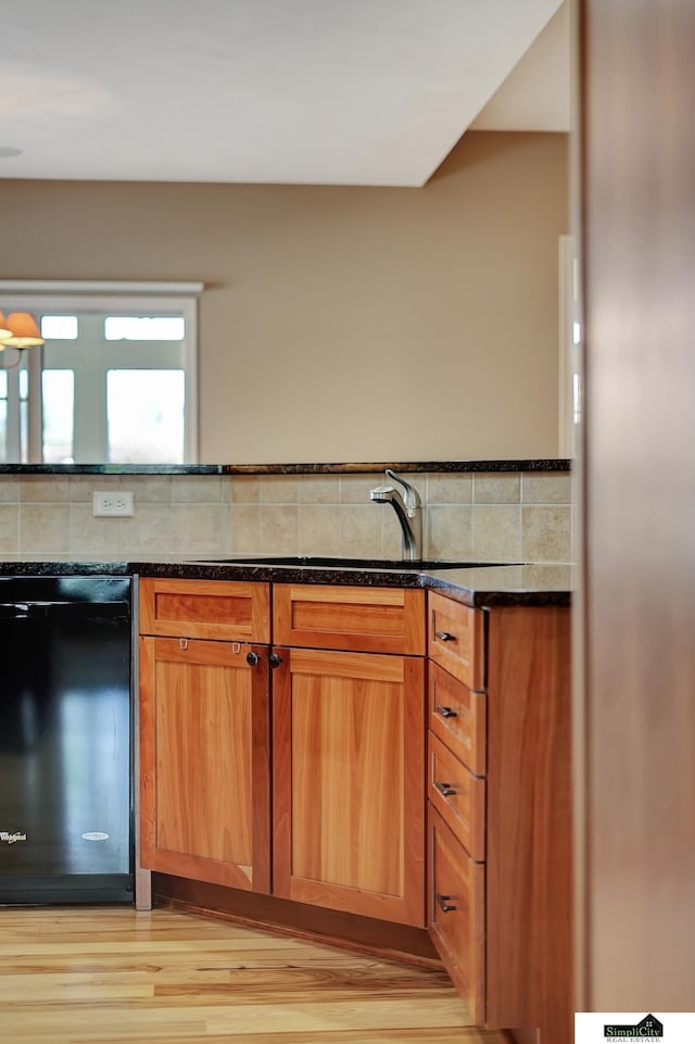8420 Augusta Dr, Lincoln, NE 68526 - kitchen featuring black dishwasher, dark stone countertops, light wood finished floors, brown cabinetry, and backsplash