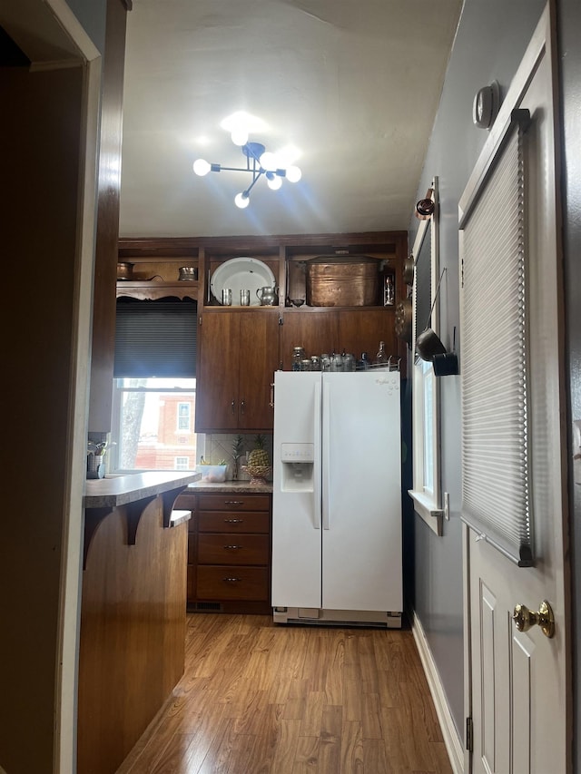 803 6th St, Fairbury, NE 68352 - kitchen with white refrigerator with ice dispenser, light wood-style floors, tasteful backsplash, and a kitchen bar