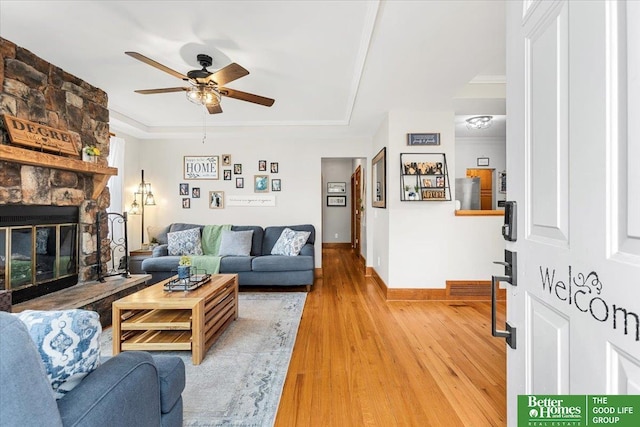 4188 Chicago St, Omaha, NE 68131 - living area with a ceiling fan, light wood finished floors, a tray ceiling, baseboards, and a stone fireplace