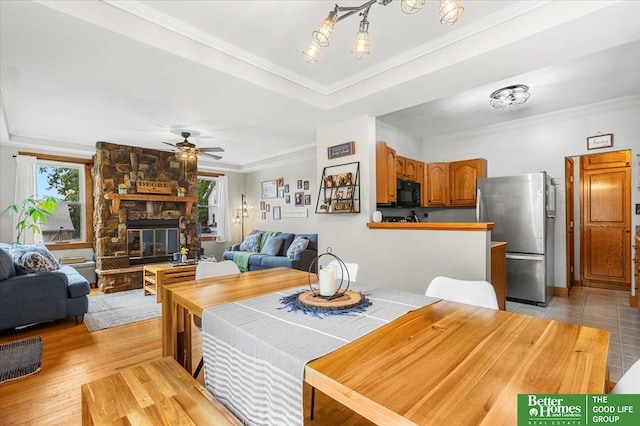 4188 Chicago St, Omaha, NE 68131 - dining space with ornamental molding, a ceiling fan, a fireplace, and a tray ceiling